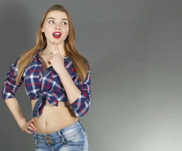 Aantrekkelijk coquet sexy meisje stand tegen de grijze achtergrond en tonen emotie verrassing — Stockfoto