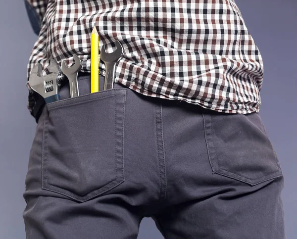 Clés et outils, crayon jaune dans une poche hanche de pantalon homme sur fond gris — Photo