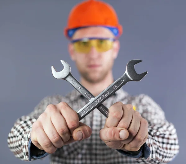  Modern genç işçi elinde iki wrenchs. Bulanık yüz
