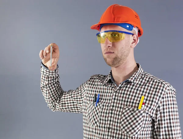 Um parafuso longo na mão de jovem trabalhador em capacete e óculos . — Fotografia de Stock