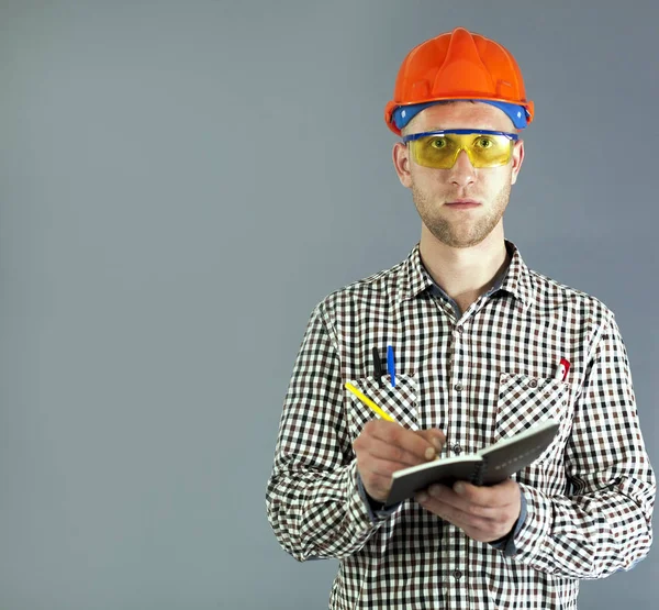 Instalatér nebo mladý dělník v helmu a brýle připraven psát objednávky. — Stock fotografie