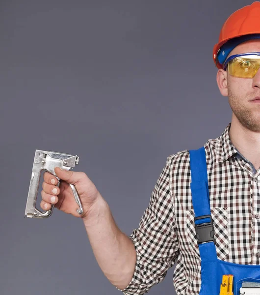 Jovem trabalhador mantém grampeador industrial riscado. Imagem recortada — Fotografia de Stock