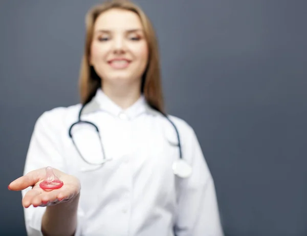 Doctor, la enfermera ofrece sexo seguro. Condón rojo en la palma. Imagen conceptual para la vida en salud — Foto de Stock