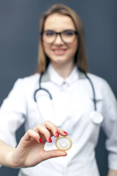 Médico joven en gafas con condón en la palma de la mano. Imagen conceptual — Foto de Stock
