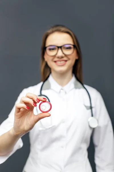 Médico joven en gafas con condón rojo en la palma de la mano. Imagen conceptual — Foto de Stock