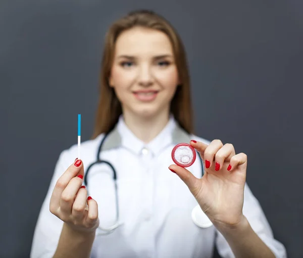 Atractivo médico mujer con condón en la palma y la prueba de embarazo — Foto de Stock