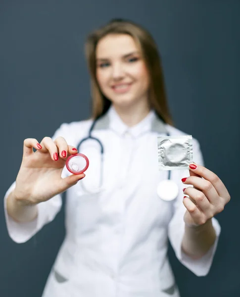 Atractiva figura médica borrosa con condón rojo en la palma de la mano. Imagen conceptual — Foto de Stock