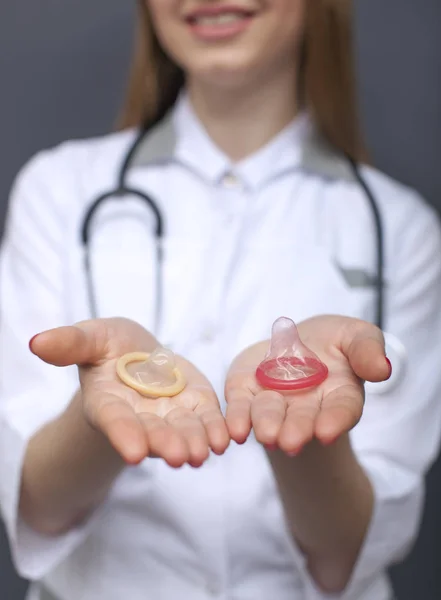 Figura médica de mujer borrosa con dos condones en las palmas de las manos. Imagen recortada conceptual — Foto de Stock