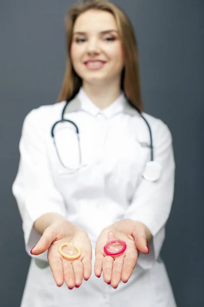 Mujer joven figura médica con dos condones en las palmas de las manos. Imagen recortada conceptual — Foto de Stock