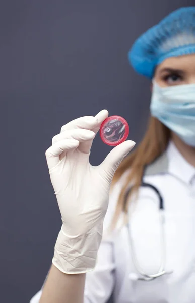 Mujer doctora, enfermera enmascarada con condón en la palma. Imagen recortada conceptual —  Fotos de Stock
