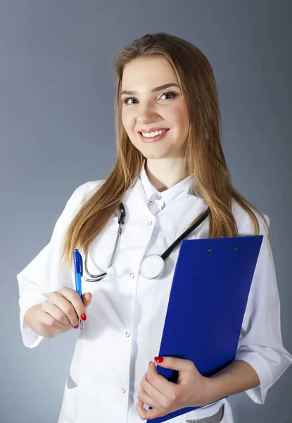 Atractiva doctora sonriente, enfermera sosteniendo una tableta de papel y una pluma — Foto de Stock