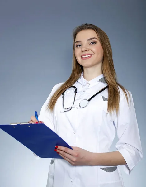 Joven mujer sonriente médico, enfermera con tableta de papel y pluma se ve directo — Foto de Stock