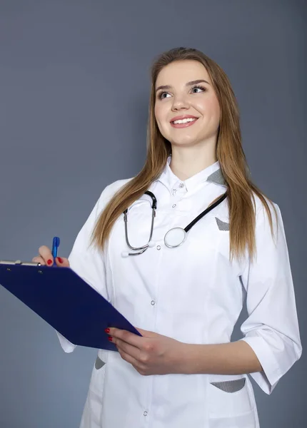 Joven mujer sonriente médico, enfermera con tableta de papel y pluma mira hacia arriba — Foto de Stock