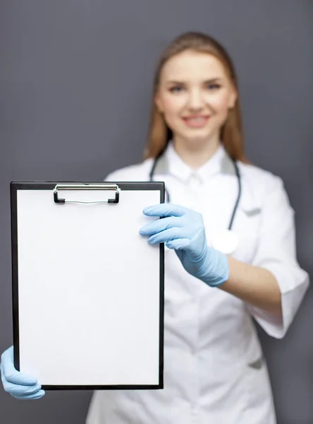 Joven mujer sonriente médico, enfermera mostrar tableta de papel. Lugar para el texto Imágenes de stock libres de derechos
