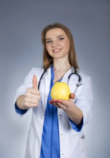 Young woman doctor holds on palm natural apple and  finger up. — Stock Photo, Image