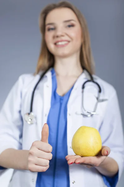 Woman doctor holds natural apple and  finger up. Health symbol — Stock Photo, Image
