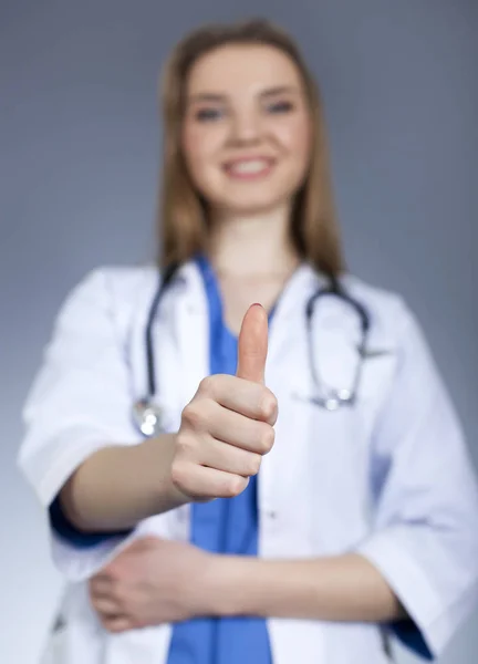 Young woman doctor holds   finger up and smile. Blurred figure — Stock Photo, Image