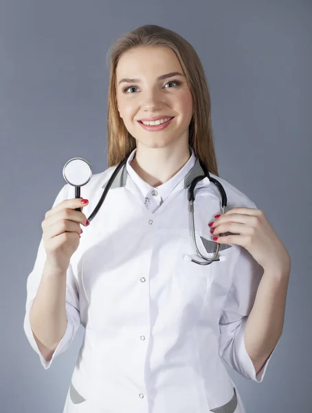 Ärztin in weißer Uniform hält Stethoskop und lächelt. Verschwommene Zahl — Stockfoto