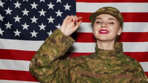 4K. Jovencita soldado con maquillaje de pie y sonrisa delante de la bandera de EE.UU. — Vídeo de stock