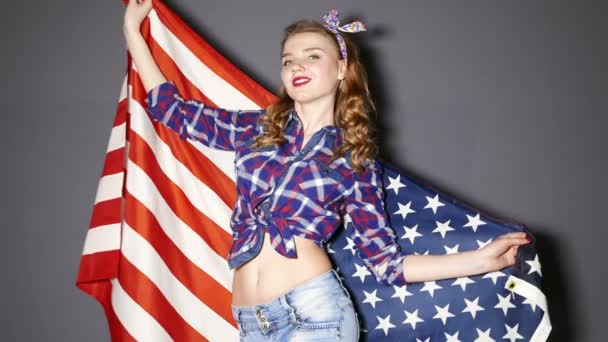 4К. Сексуальная девушка танцует с американским флагом и улыбается. Медленное движение — стоковое видео