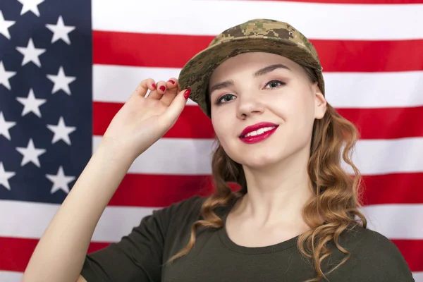 Çekici kadın asker stand önünde Amerikan bayrağı gülümseyen.