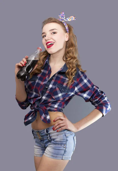 Mladá dívka s láhev černý nápoj coquets, jazykem visí ven — Stock fotografie
