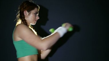  Çekici genç kadın kutusunu koyu arka plan önünde dumbbells ile spor
