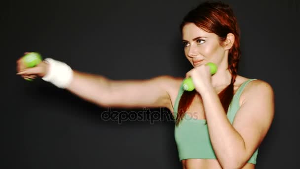 暗い背景の前でダンベルを持つ若い魅力的なスポーツ女性ボックス — ストック動画