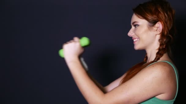 Atractiva mujer sonriente entrena con pesas verdes — Vídeo de stock