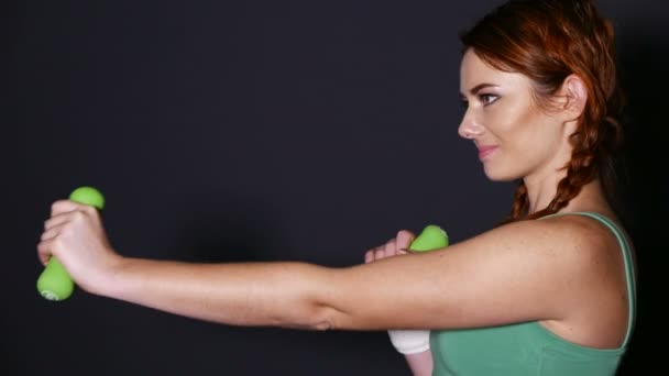 Atractiva mujer sonriente entrena con pesas verdes — Vídeo de stock