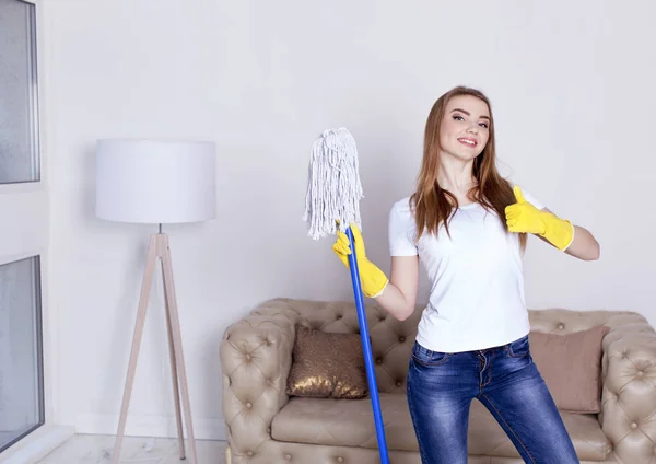 Ritratto di giovane donna felice che fa faccende di pulizia a casa con le dita alzate Foto Stock Royalty Free