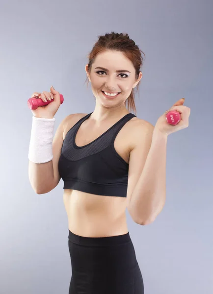  Gri arka plan önünde kırmızı dumbbells ile gülümseyen spor doğrudan görünüyor