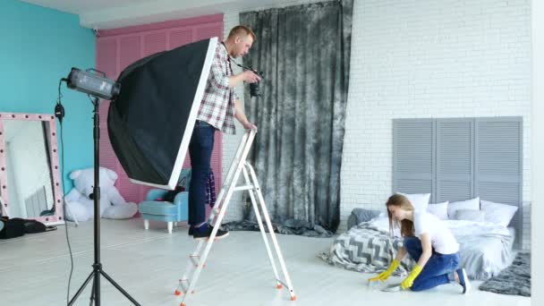 Fotoestudio detrás del escenario. Hombre fotógrafo explicar poses a mujer modelo como ama de casa . — Vídeo de stock