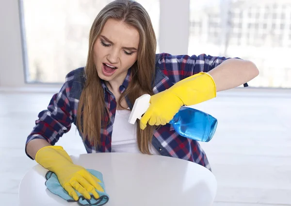 Mujer joven limpiando polvos en la mesa, emoción en la cara — Foto de Stock
