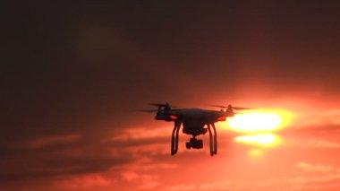Drone günbatımı kırmızı gökyüzü önünde uçan. Modern teknolojiler ve doğa