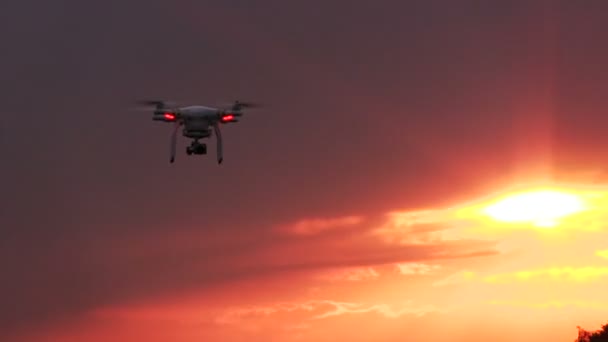 Drone voador em frente ao céu vermelho do pôr-do-sol. Tecnologias modernas e natureza — Vídeo de Stock