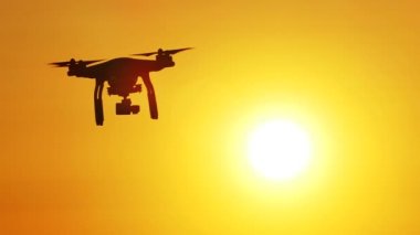 Yavaş silüeti dron turuncu gökyüzü önünde uçan. Modern teknolojiler 