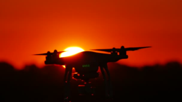 Siluetti hitaasti lentävä drone edessä auringonlaskun punainen taivas. Nykyaikainen teknologia — kuvapankkivideo