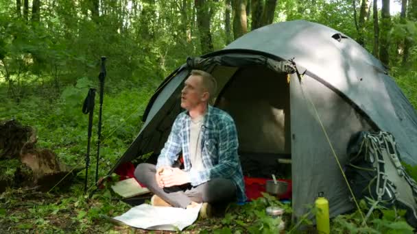 4K. Homem caminhante chá bebida turística perto de tenda na floresta de primavera. Equipa de turismo — Vídeo de Stock