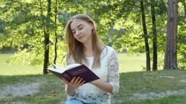 4 k. çekici smiloing kız parkta İncil okur. Hıristiyan takım vurdu