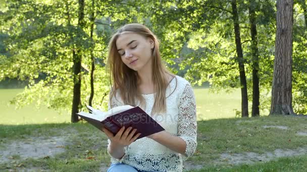 4k. Attraente sorridente ragazza legge la Bibbia nel parco. Squadra cristiana colpita — Video Stock