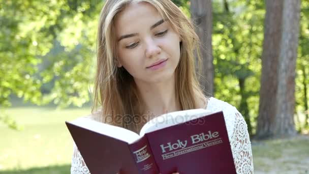 4K. Menina atraente lê Bíblia no parque. Equipe cristã tiro, close-up — Vídeo de Stock