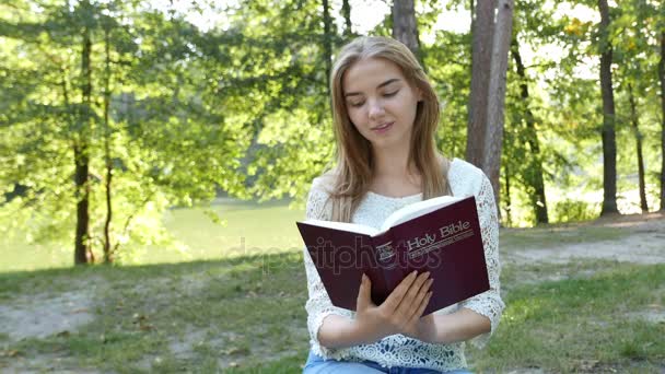 4k. Moderne meisje leest de Bijbel in het park. Christelijke team — Stockvideo