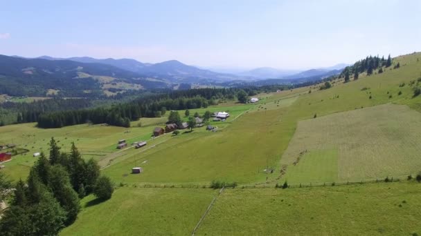 4k. Luchtfoto landschap. Bergen, bos, weide, blauwe hemel en klein dorp — Stockvideo