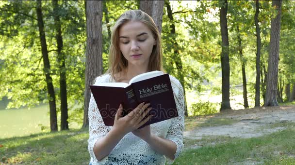 4k, UHD, 3840, 1 person, backgrounds, bible, book,belief, christ, christianity, Christian, church, color, contains people, cross, day, female, girl, god,  white, image, jesus, lake,  medium shot, natural lighting, nature, pray, praying, read, real ti — Stock Video