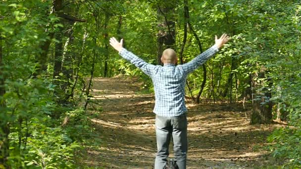 Uomo su ruota mono in legno autunnale con le mani alzate, rallentatore . — Video Stock