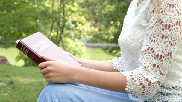 4k. Cuerpo de chica al aire libre con Biblia. Estudiar el cristianismo, la oración — Vídeos de Stock