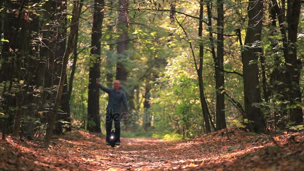 Homem montando roda mono no outono ensolarado madeira e fazer foto selfie por smartphone — Vídeo de Stock