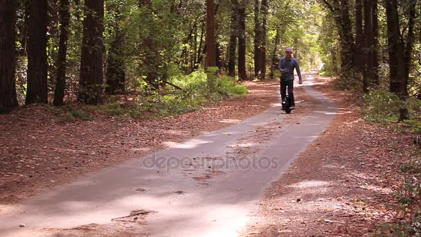 秋の公園道路でモノラルのホイールを持つ男を話す携帯電話スマート フォン — ストック動画