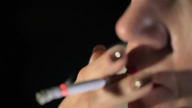 Kadın kırmızı dudaklar ile sigara içiyor ve duman exhales. Bulanık yüz. Aşırı yakın çekim